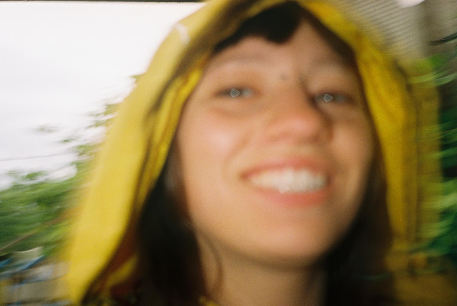 A blurry photo of a woman. She smiles and looks into the camera.